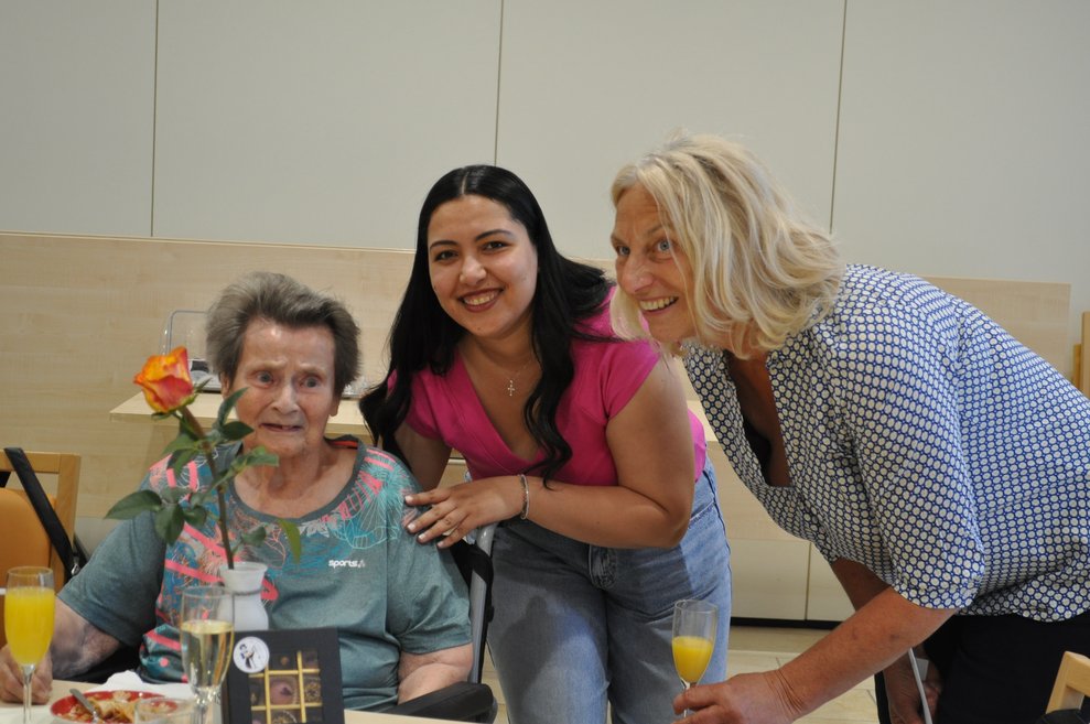 eine ältere Dame mit Blumen und zwei Frauen 