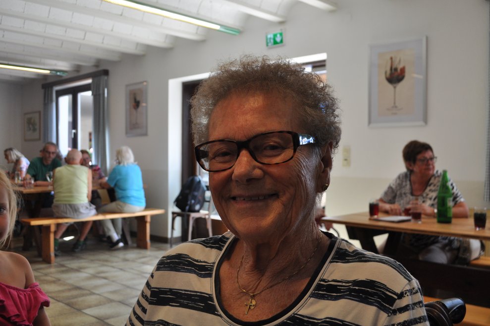 eine ältere Frau beim Heurigen