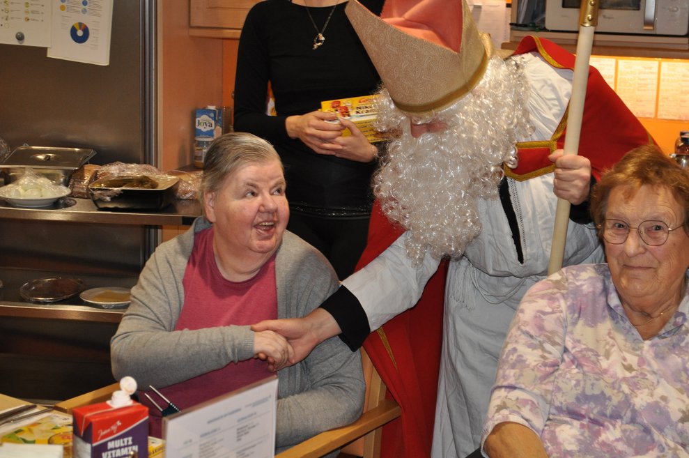 ein Mann als Nikolaus verkleidet gibt einer älteren Dame die Hand