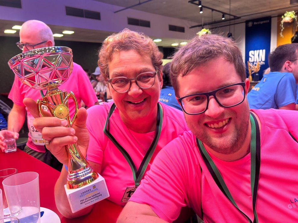 ein Mann und eine Frau mit pinken Sport T-Shirts, Medaillen und Pokal