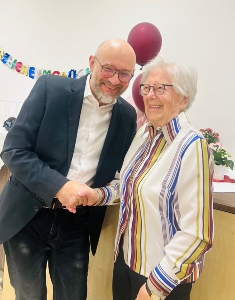 ein Mann gibt einer älteren Dame die Hand zur Gratulation zum 101. Geburtstag
