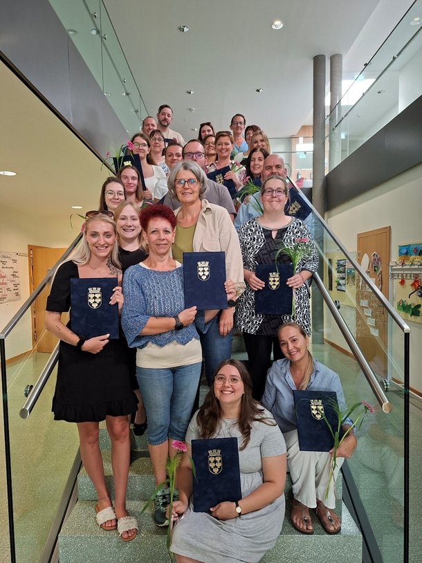 mehrere Personen mit Blumen und Urkunden