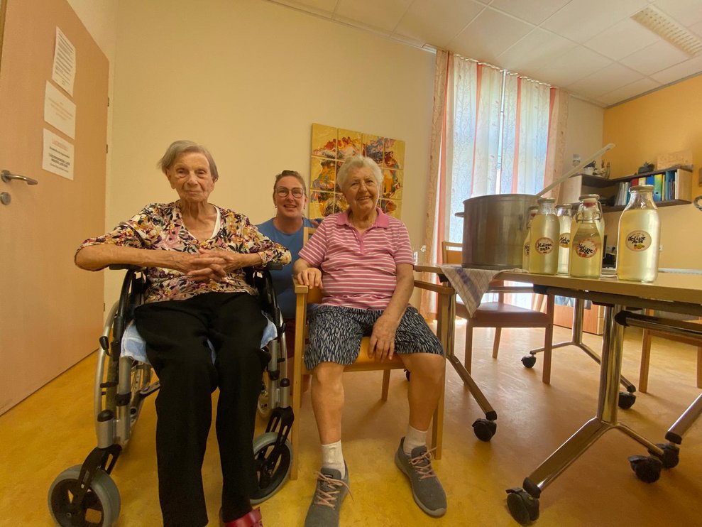 Zwei ältere Damen und eine jüngere Frau beim Melissensaft produzieren