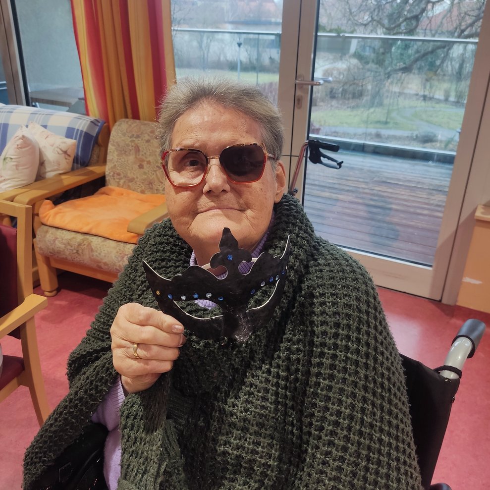eine ältere Dame mit einer selbstgebastelten Faschingsmaske