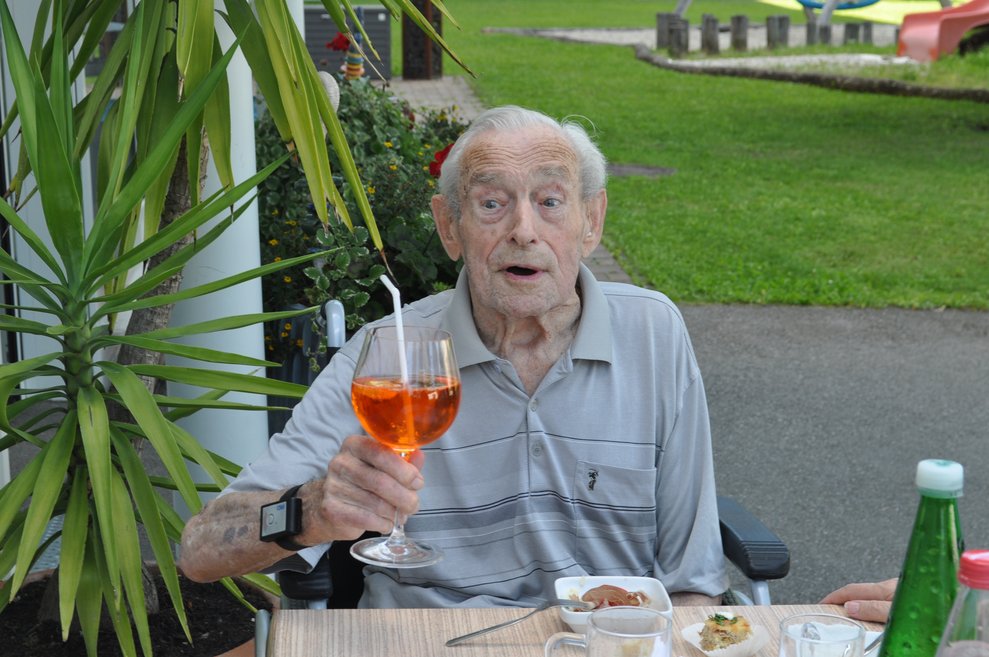 ein älterer Herr mit einem Aperol Spritzer