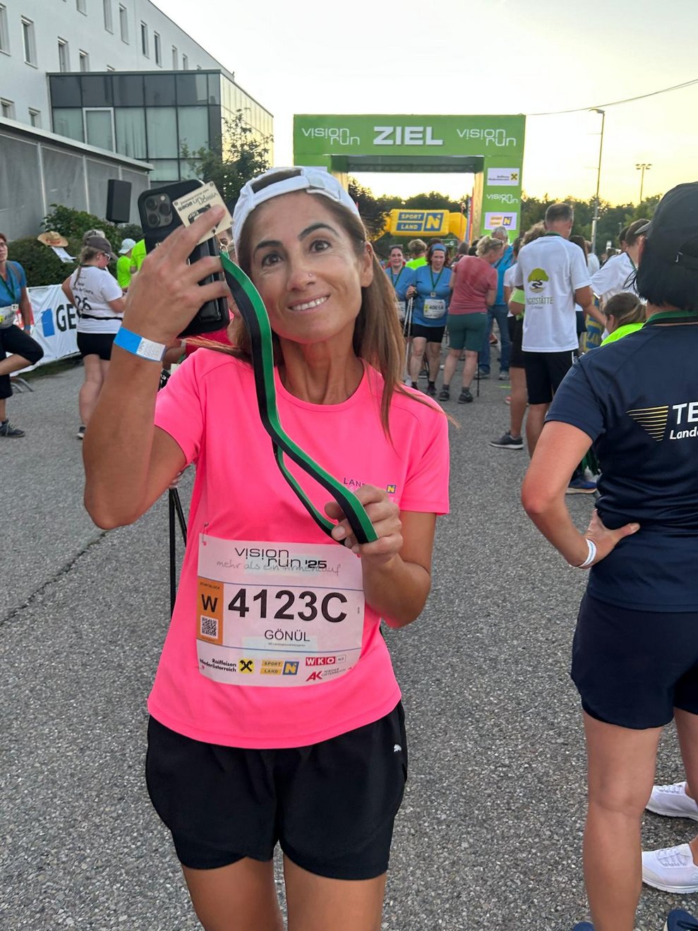 eine Frau ganz froh im Ziel, mit einer Medaille um den Hals