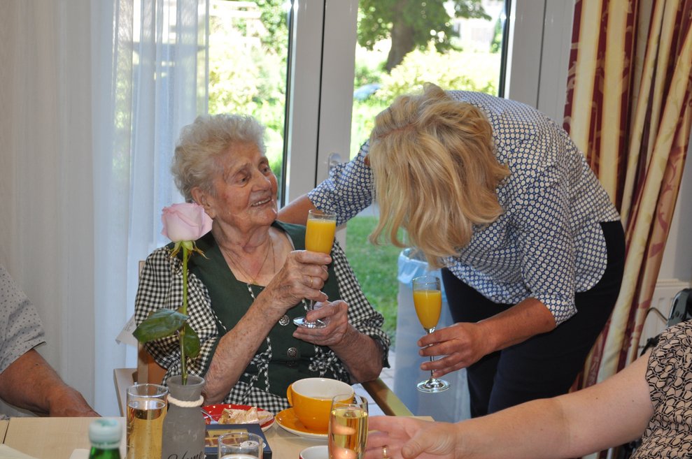 eine Frau gratuliert einer älteren Dame zum Geburtstag