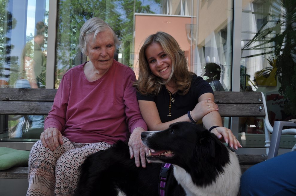 ein junges Mädchen und eine ältere Frau streicheln einen Hund