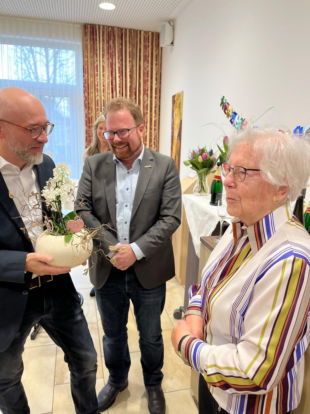 ein Mann überreicht einer älteren Dame Blumen zum Geburtstag