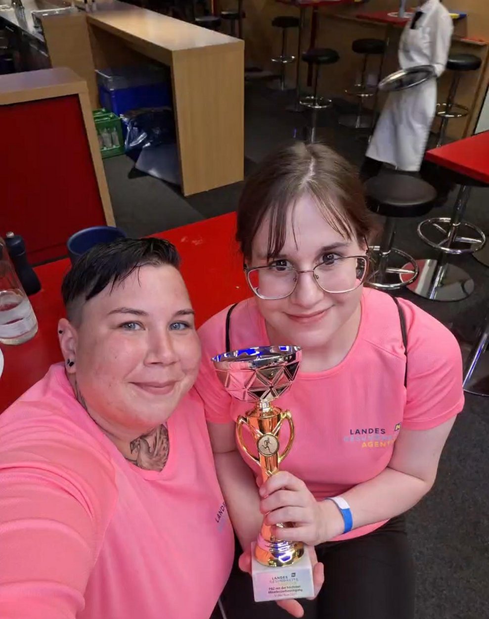 Zwei Frauen mit pinken Sport T-Shirts, Medaillen und Pokal