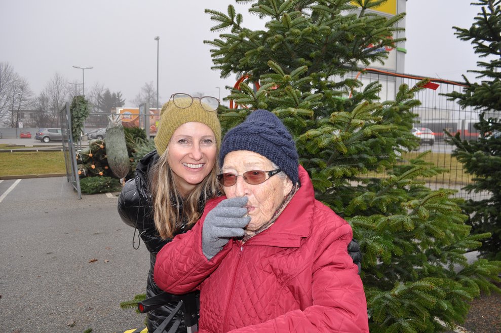 eine ältere Dame und eine jüngere Dame beim Christbaum aussuchen