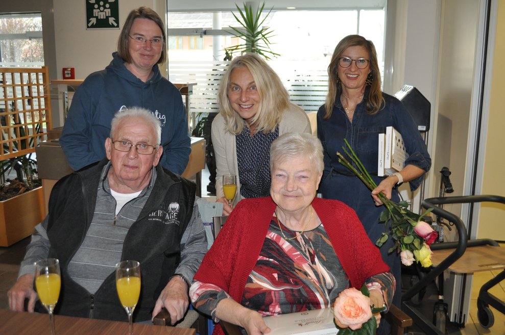 ein Gruppenfoto mit einigen Personen bei einer Geburtstagsfeiermit Pralinen, Sekt und Blumen 
