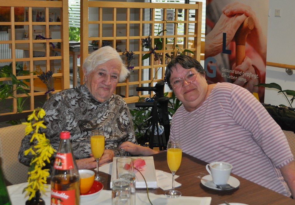 2 Damen sitzen bei gedecktem Tisch und feiern Geburtstag.