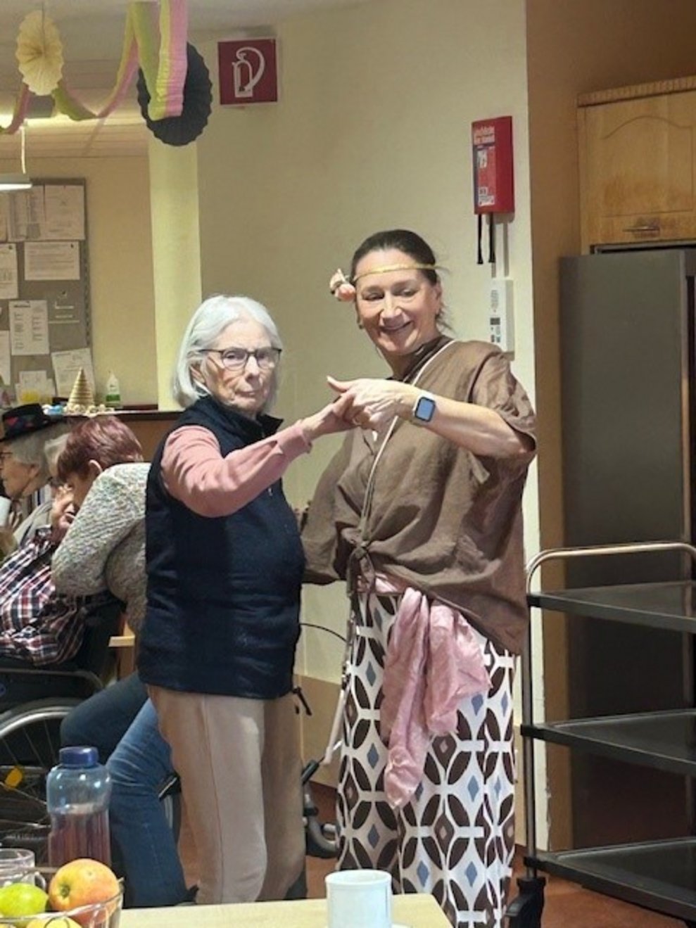 eine Frau verkleidet als Hippie mit einer älteren Dame beim Tanzen