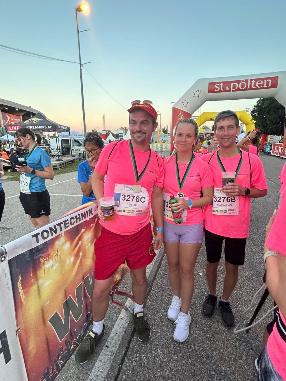 Drei Personen im Ziel mit Medaillen