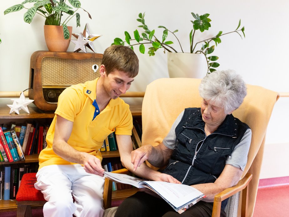 Ein Betreuer sitzt neben einer Bewohnerin.