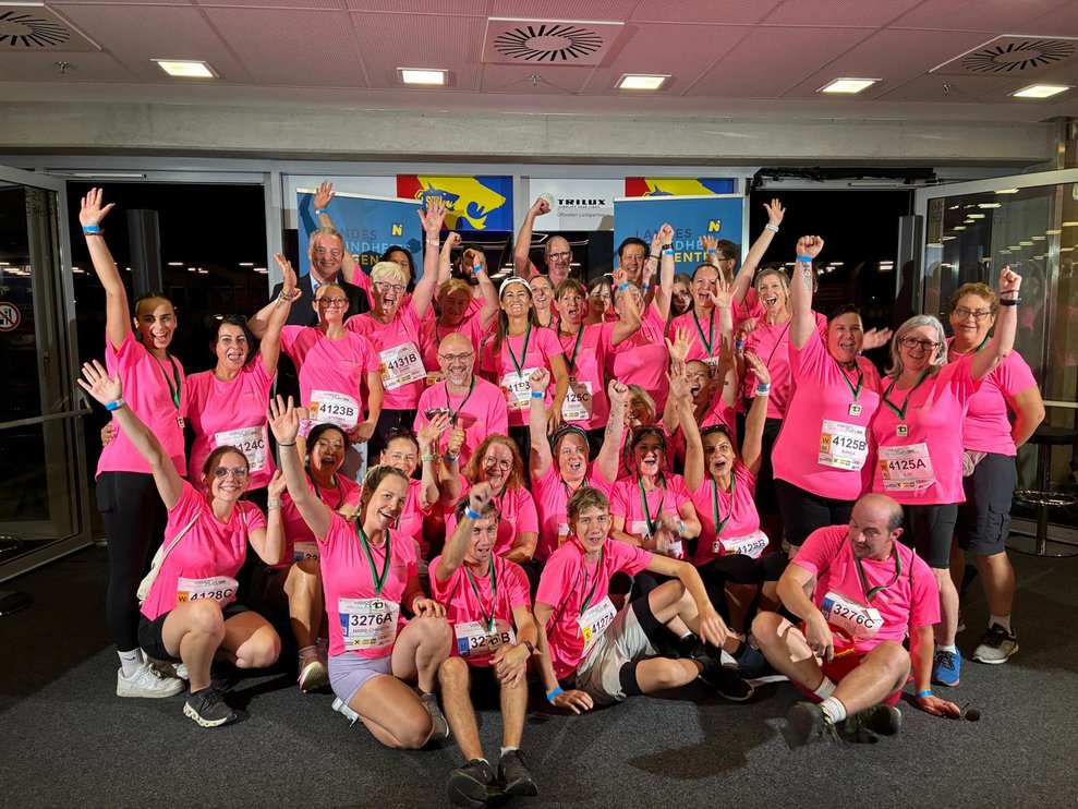 Mehrere Personen in pinken Sport T-Shirts auf der Bühne jubelnd