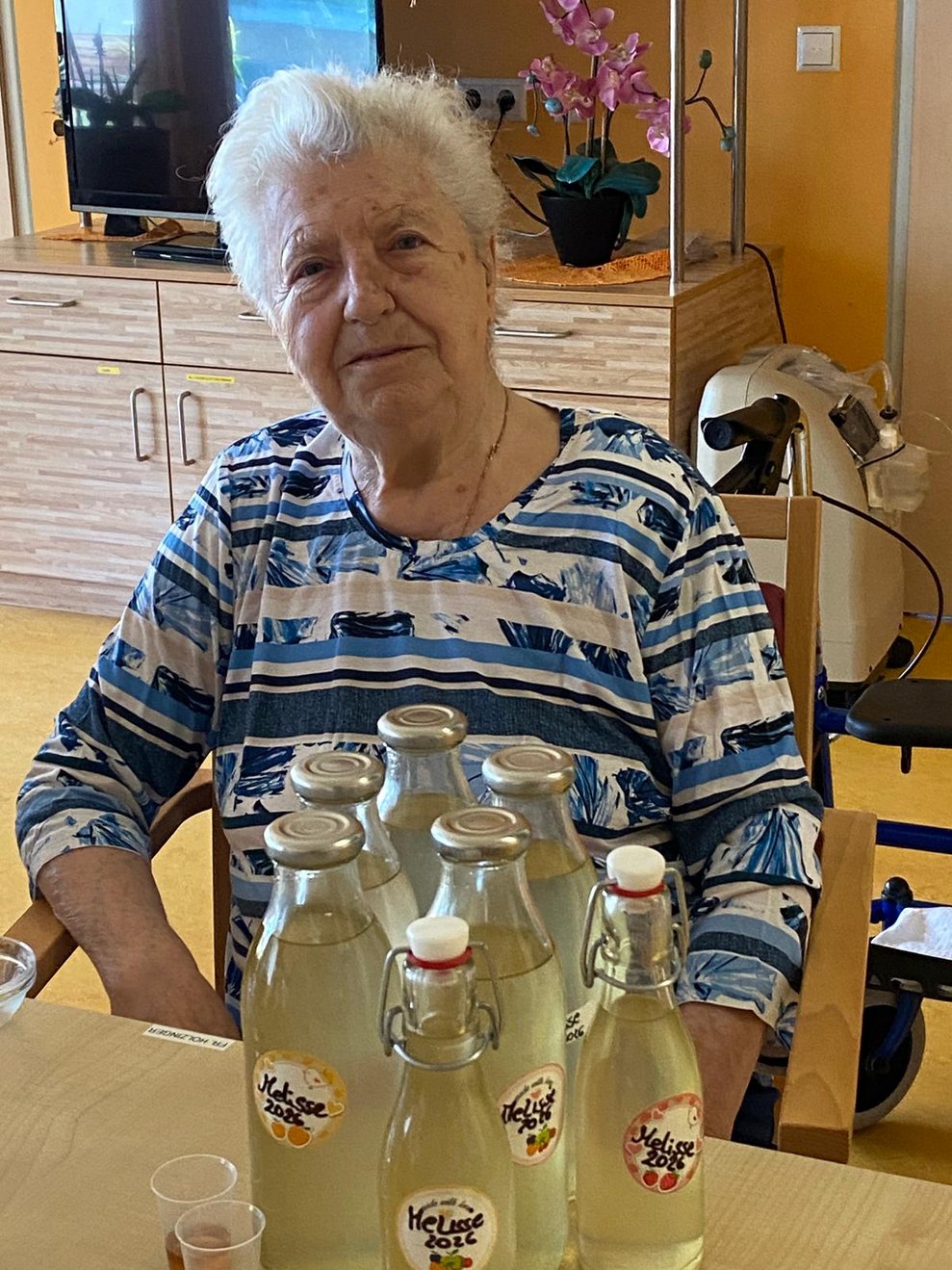 eine ältere Dame und einige Flaschen Melissensaft