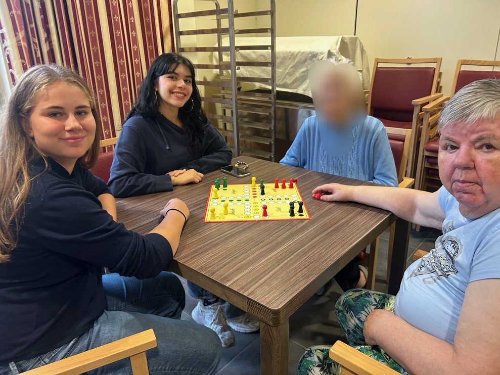 Zwei Schülerinnen mit Bewohnerinnen bei Brettspielen