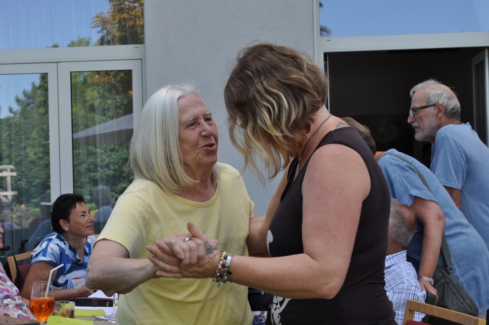 eine Mitarbeiterin bittet eine ältere Dame um ein Tänzchen