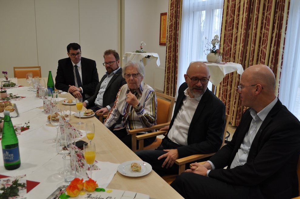 einige Personen sitzen bei Tisch bei einer Geburtstagsfeier