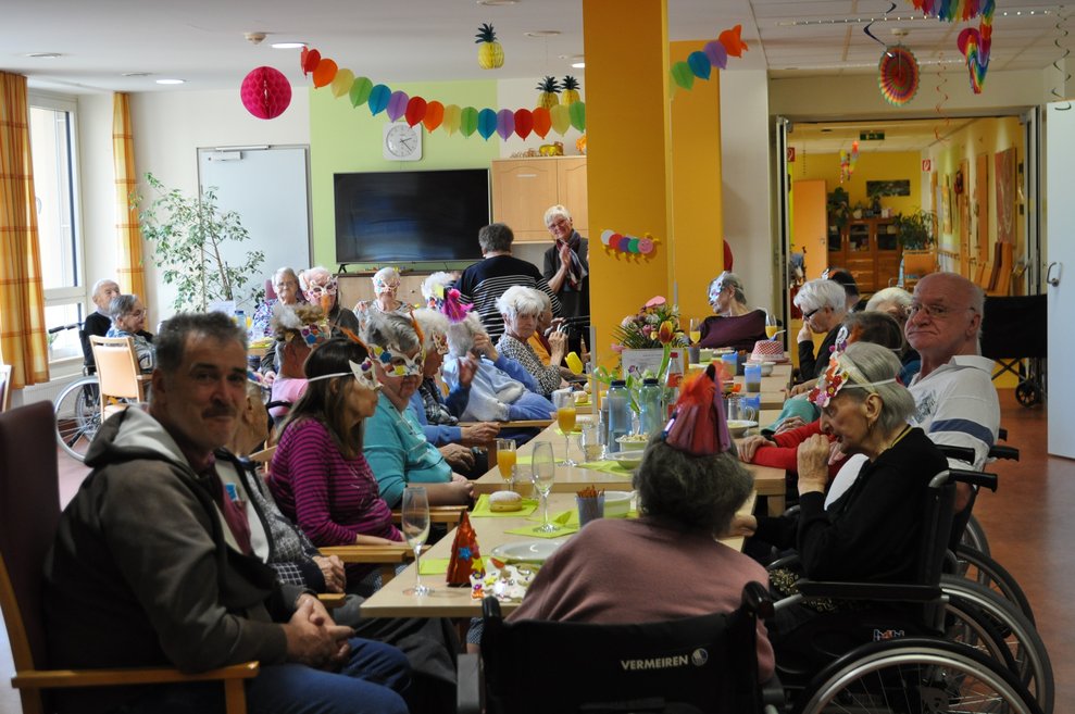 ein großer Tisch mit älteren Menschen und Faschingsdekoration