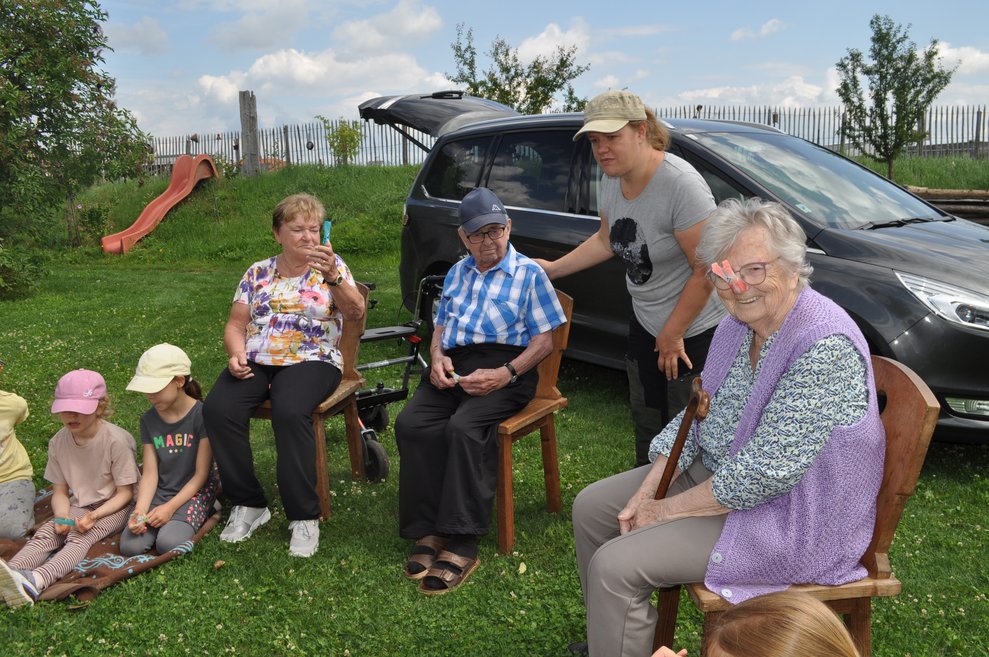 einige ältere Menschen und Kinder sitzen in der Wiese