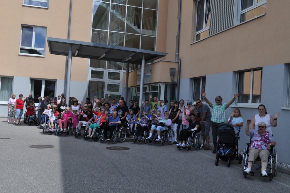 mehrere Menschen vor dem Pflegeheim mit Rollatoren, Rollstühlen