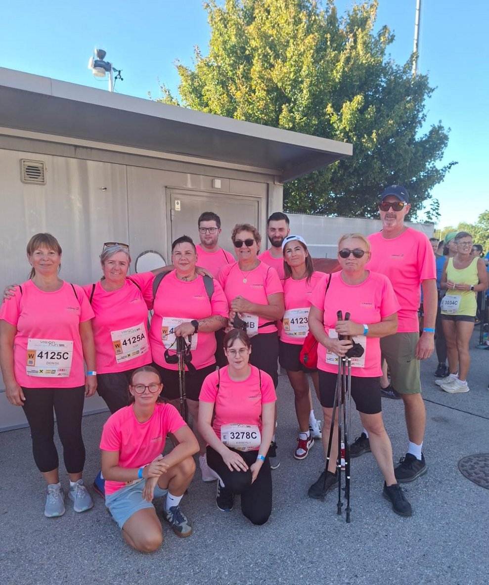 Mehrere Personen mit pinken Sport T-Shirts, Medaillen und Pokal