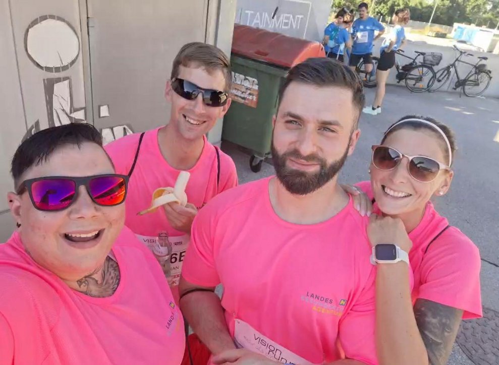 ein ManMehrere Personen mit pinken Sport T-Shirts, Medaillen und Pokal