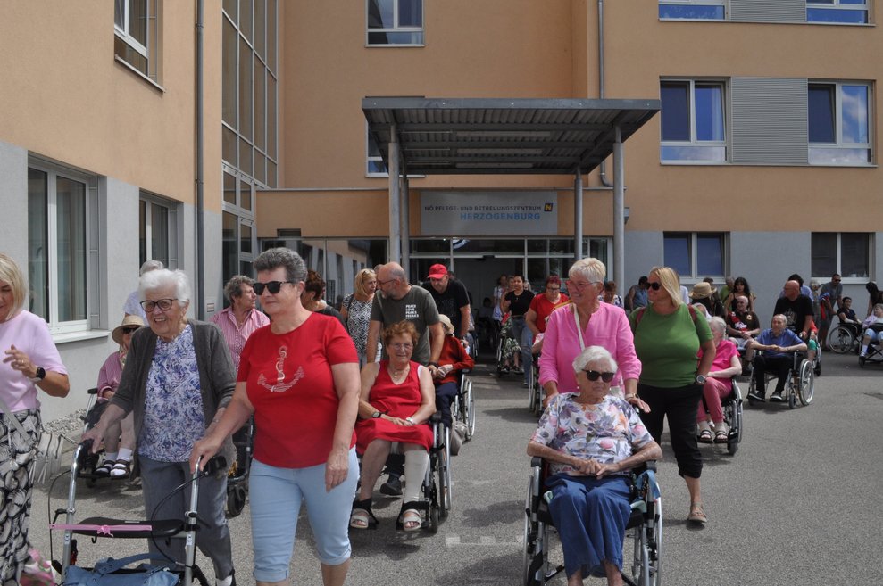 einige Personen gehen mit Rollator oder fahren im Rollstuhl