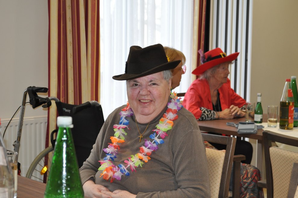 eine ältere Dame verkleidet mit Hawai Kette und Hut