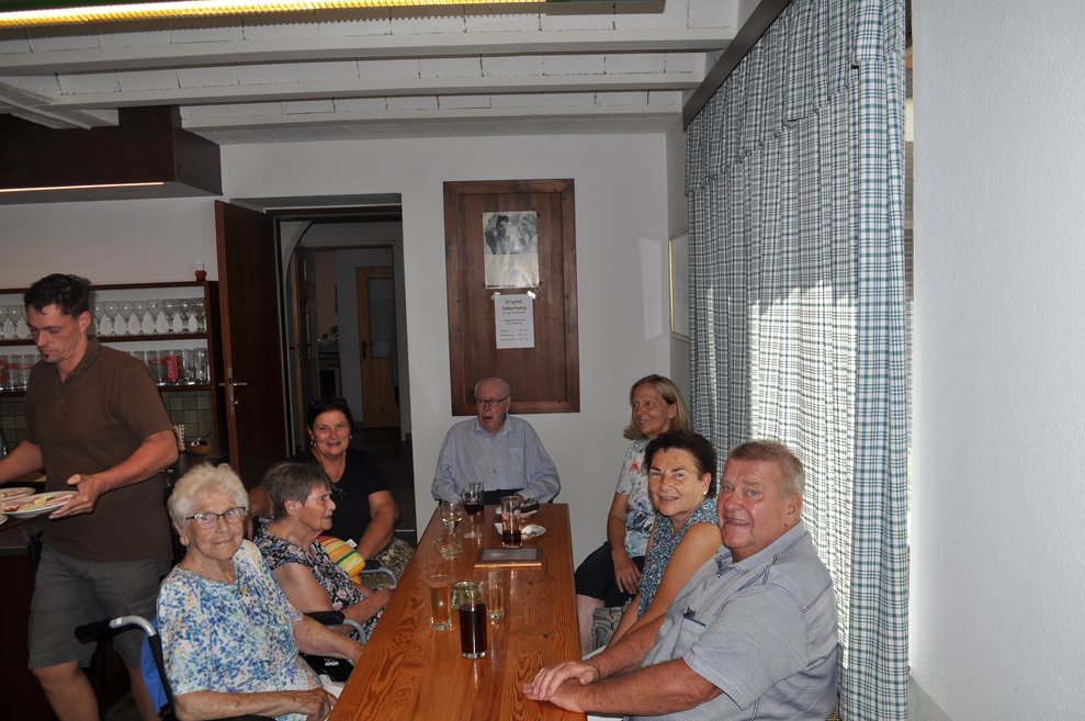 eine gesellige Runde von älteren Menschen beim Heurigen