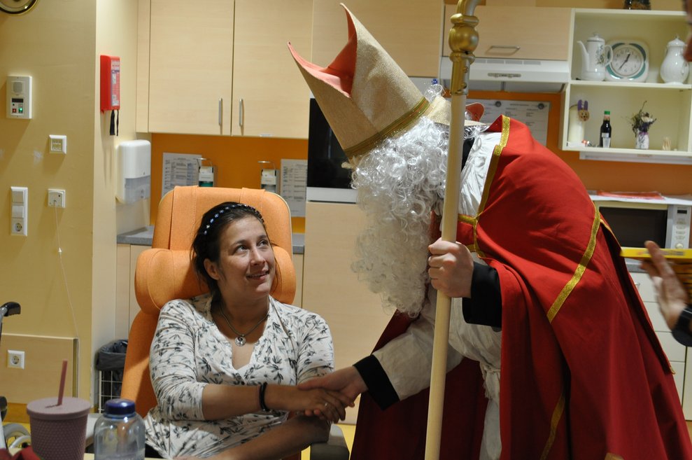 ein Mann als Nikolaus verkleidet zu Besuch bei einer Dame im Pflegeheim
