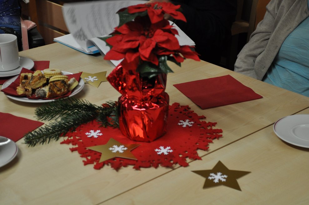 einige ältere Menschen mit Weihnachtsmann Mützen bei weihnachtlich dekorierten Tischen