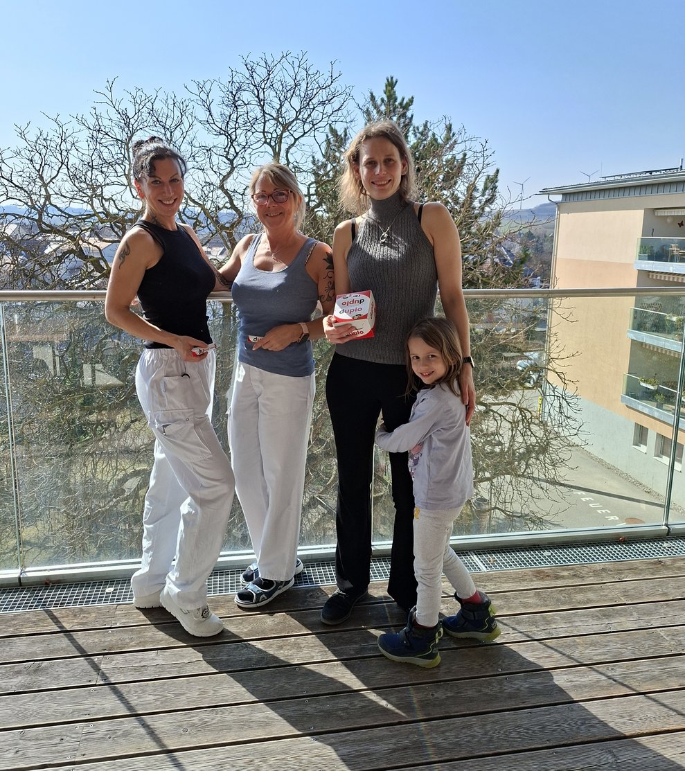 3 Mitarbeiterinnen und 1 Mädchen am Balkon bei der Übergabe der Duplo Riegel.