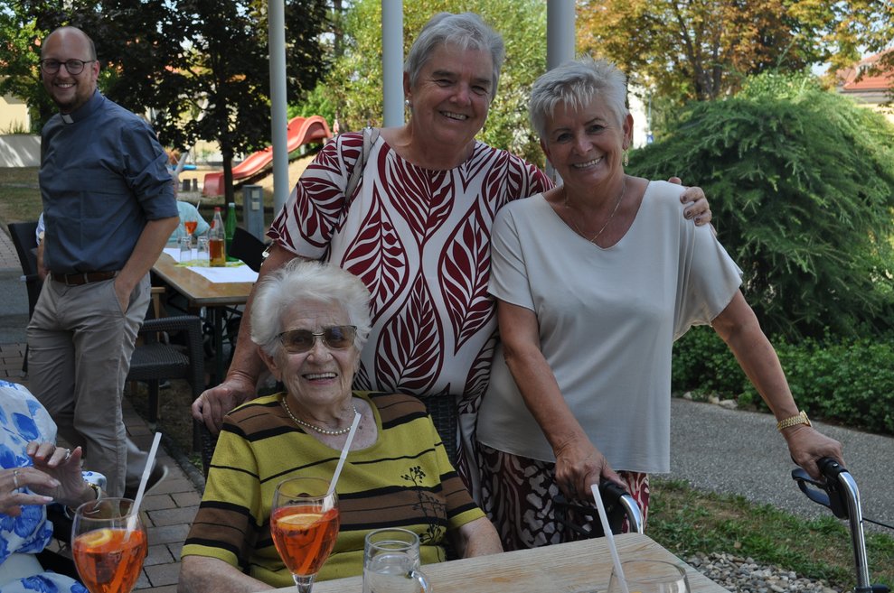 eine ätere Frau und zwei andere Frauen im Bild mit Aperol Spritzer im Garten