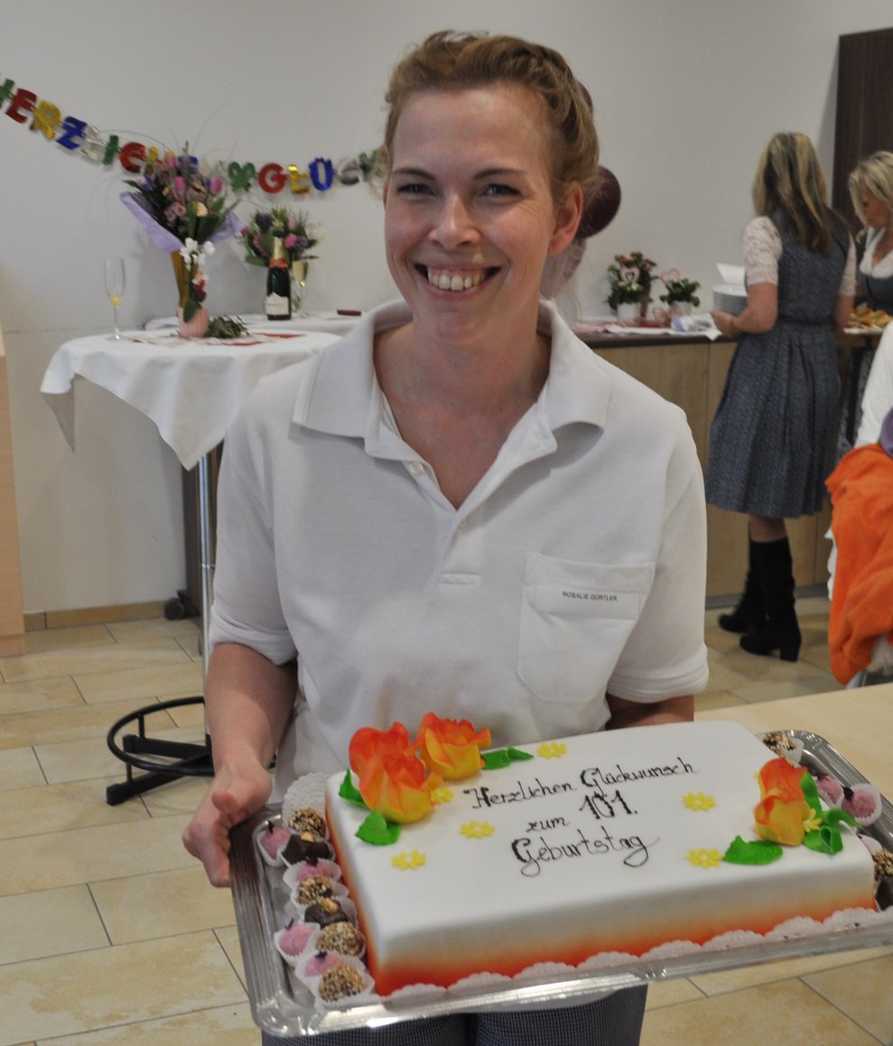 eine Frau mit einer Geburtstagstorte mit Schriftzug "Herzlichen Glückwunsch zum 101.Geburtstag"