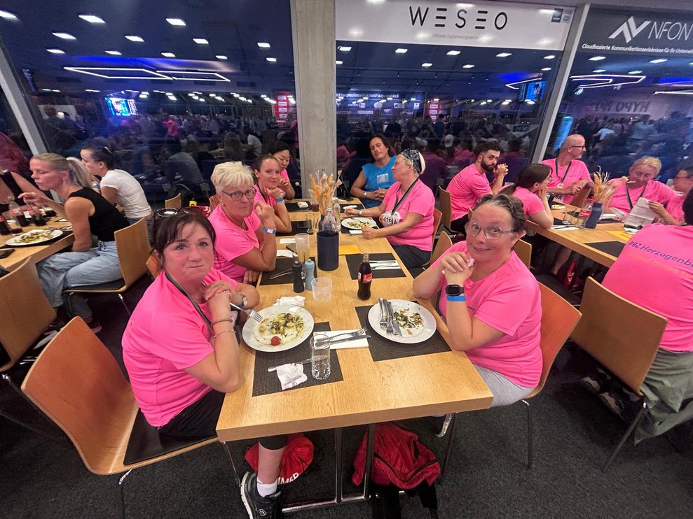 einige Personen mit pinken Sport T-Shirts bei Tisch beim Abendessen