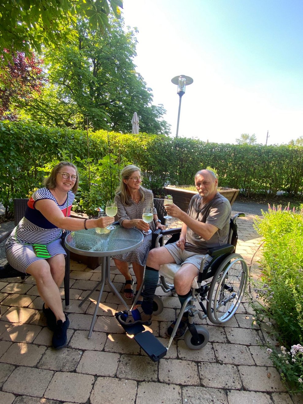 Drei Personen sitzen im Garten und trinken Melissensaft