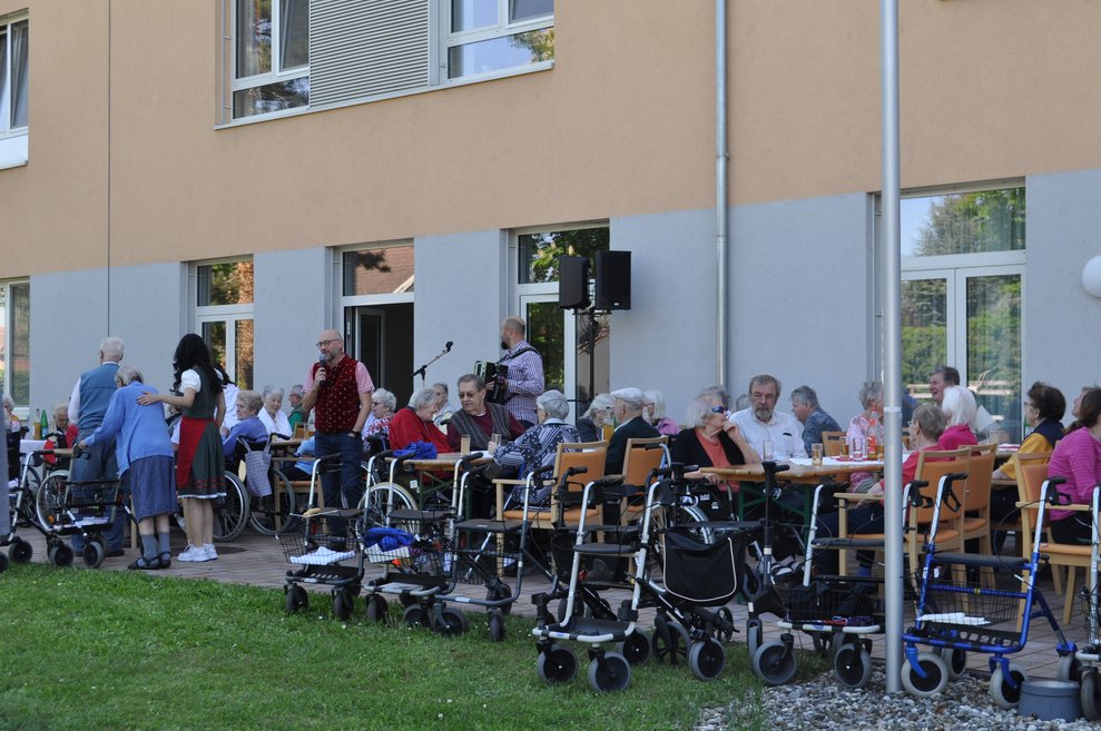 mehrere Bewohnerinnen und Bewohner im Garten bei der Maibaumfeier