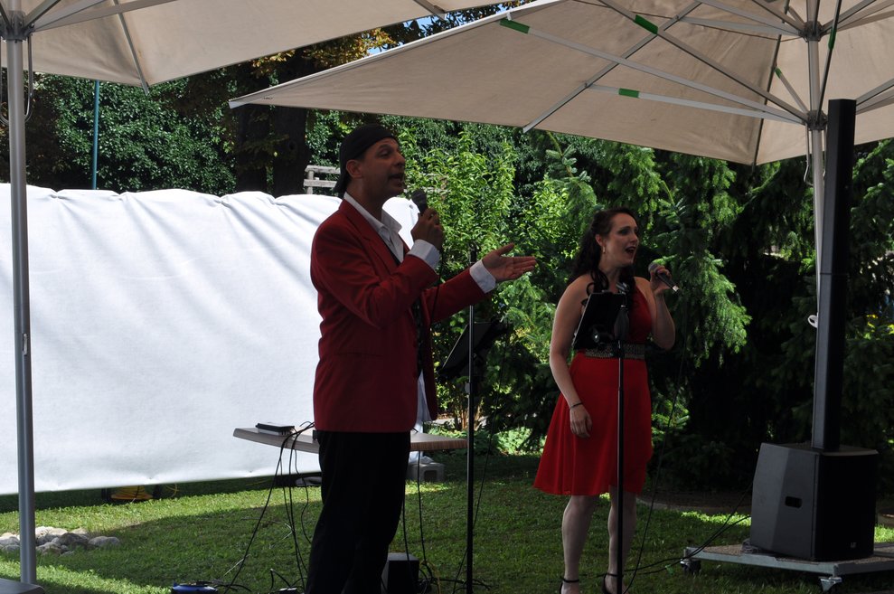 Ein Herr und eine Frau singen im Garten unter dem Sonnenschirm