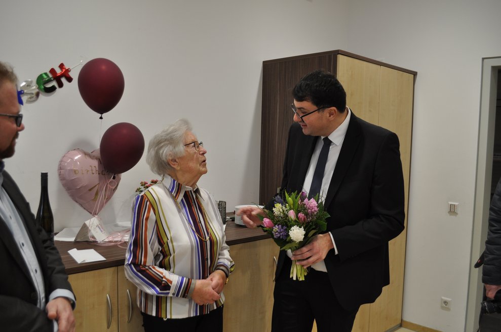 ein Herr überreicht einer älteren Dame Blumen zum 101. Geburtstag