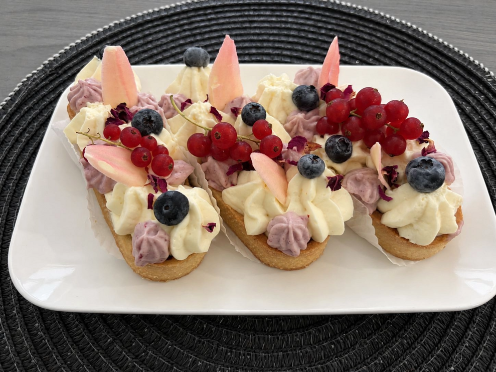 drei kleine Törtchen mit Heidelbeeren, Ribiseln und zweifärbigen Schlagobers Cremen