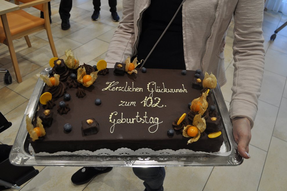 eine Schokoladen Torte mit Schriftzug "Herzlichen Glückwunsch zum 102. Geburtstag"