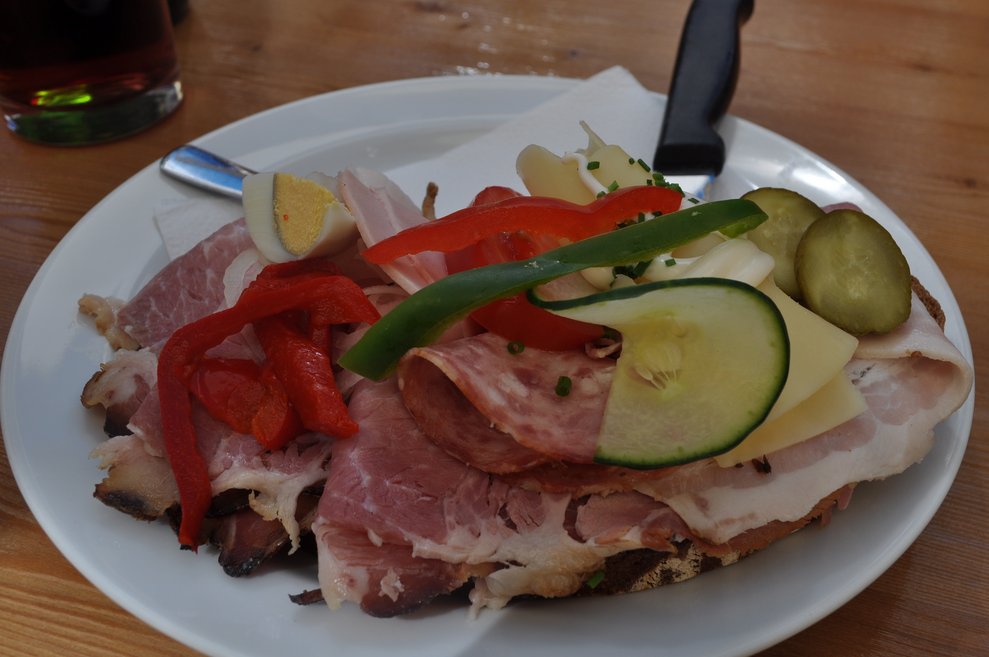 ein üppig belegtes Brot mit Geselchtem und Gemüsegarnitur