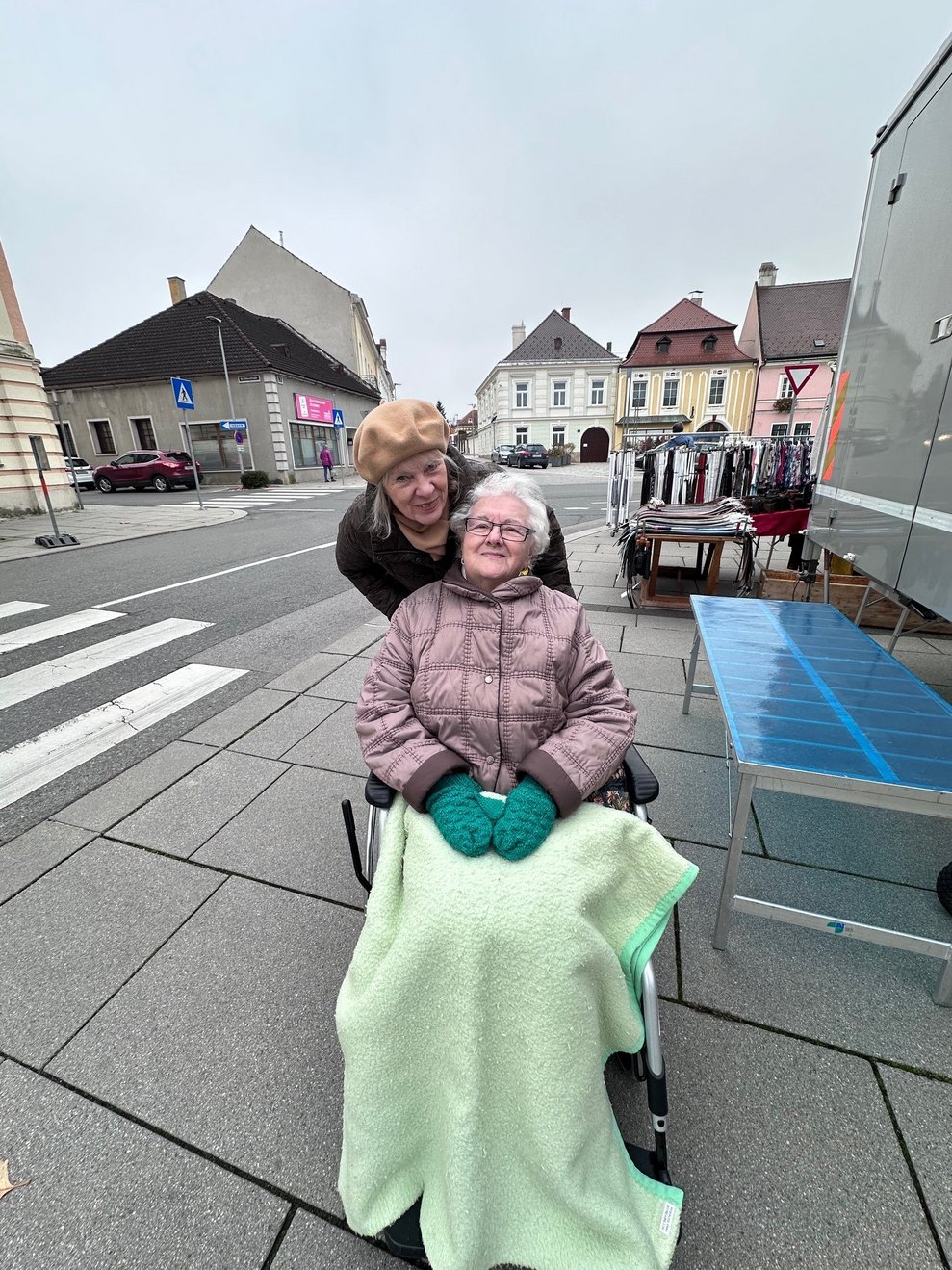 eine Dame im Rollstuhl mit einer Begleitperson am Markt