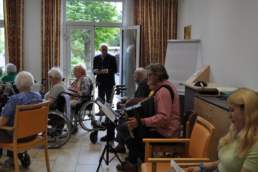 ein Mann mit einer Ziehharmonika und andere Menschen die singen