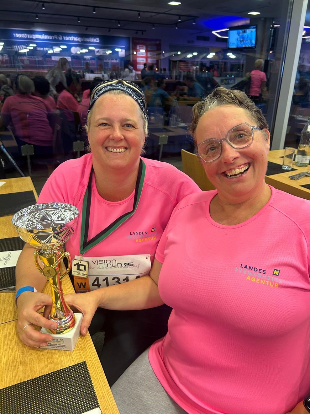 Zwei Frauen mit pinken Sport T-Shirts, Medaillen und Pokal