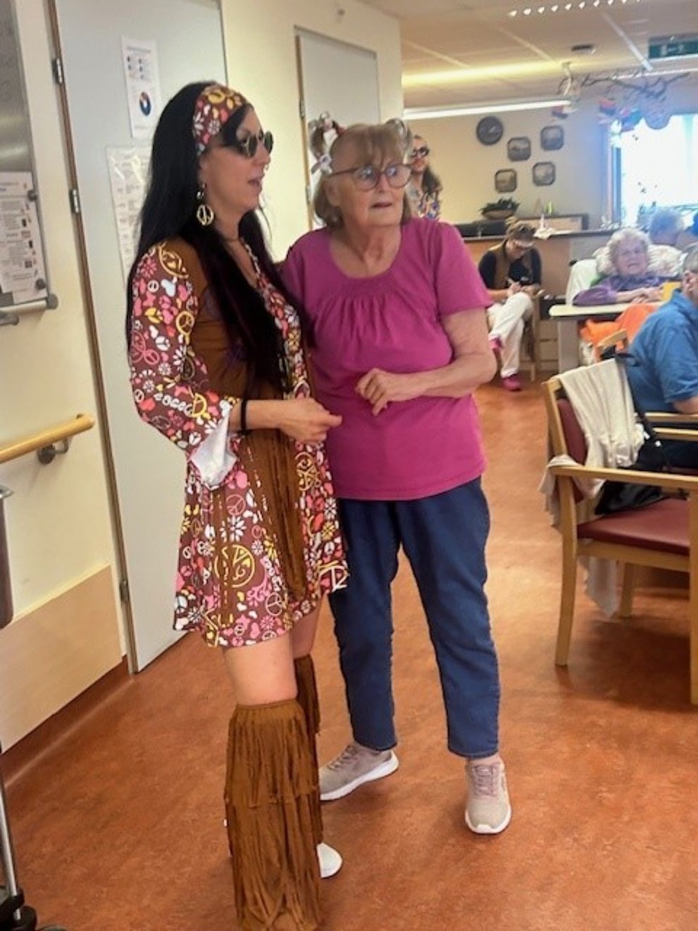 eine Frau verkleidet als Hippie mit einer älteren Dame beim Tanzen